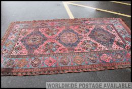 A large Turkish / Persian handwoven rug having red ground with blue spandrels and geometric black