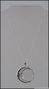 A silver white metal necklace set with a magnifying glass