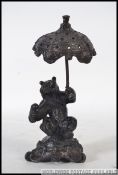 A bronze hollow cast bronze bear with umbrella raised on a naturalistic plinth base