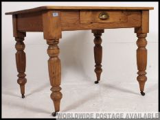 A Victorian pine kitchen dining table raised on turned reeded legs with fitted frieze having single