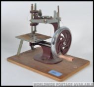 A vintage childs sewing machine raised on the original wooden plinth complete with a box L20cm