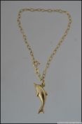 A hallmarked 9ct gold chain link bracelet with a dolphin charm. Weight 1.9g. Measures 9cms.