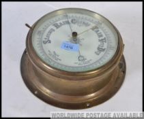 An early 20th century large brass ships bulkhead barometer with detailed white glass dial behind