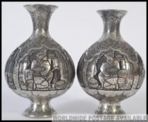 A pair of Indian white metal silver plated vases. Highly decorated with scenes to all sides.