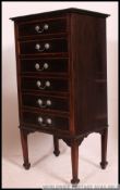 An Edwardian mahogany inlaid pedestal chest of drawers being raised on square tapered legs with pad
