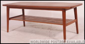 A retro 1970's teak wood coffee table raised on angular supports with rectangular table top above