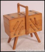 A vintage 1950's metamorphic sewing box with multiple hinged lid raised on tapered legs.