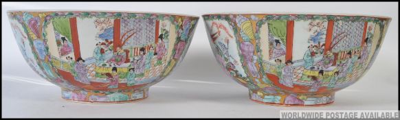 A pair of 20th century Chinese famille rose large bowls stylised with scenic cartouche panels and