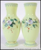 A pair of Victorian green glass handpainted vases with decorative foliate designs H29cm