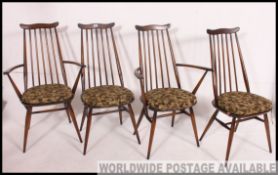A set of 4 Ercol beech and elm wood dining chairs having panel seats with arched back rests,