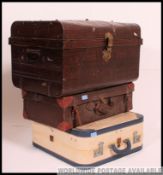 A vintage early 20th century tin tack trunk together with a leather suitcase and a two tone vinyl