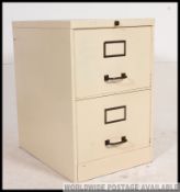 A 20th century painted metal industrial twin filing cabinet with recessed handles and paper