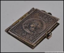 A white metal french religious pendant in the form of a book containing images of the crucifixion