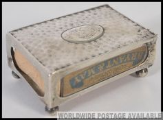 A silver hallmarked match box holder, having a central cartouche monogram, raised on bun feet,