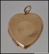 A 9ct gold locket pendant in the form of a heart with geometric etched decoration.