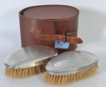 A pair of leather cased silver hallmarked gentlemens hair brushes,
