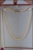 A string of cultured pearls with 9ct gold clip clasp in the form of a stylized bow set with
