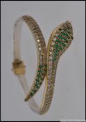 A silver metal CZ and emerald set snake bangle