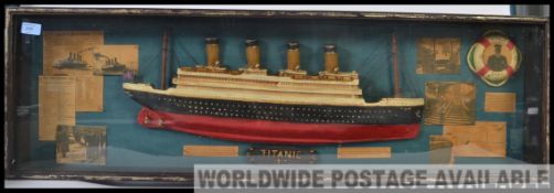 A Framed and glazed large display case with half model hull of the Titanic together with ephemera