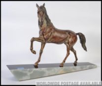 A 20th century cold cast Bronzed cantering horse set on an angular tapering marble plinth base.