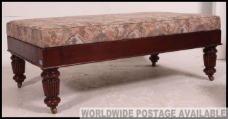 A large mahogany upholstered foot stool / pouffe raised on regency mahogany legs with castors