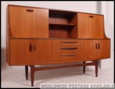 A 1970's G-Plan teak wood sideboard raised on tapered legs with a series of drawers and cupboards