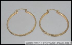 A pair of large designer hallmarked 375 9ct London gold hoop earrings with cut star decoration and