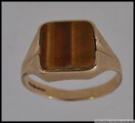 A 9ct gold gentlemans signet ring with inset tigers eye agate stone mount.