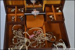 A large silk lined musical jewellery box containing a good selection of costume jewellery to