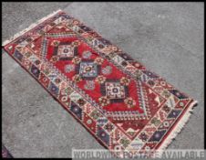 A large early 20th century handwoven rug / runner of having red ground with geometric borders and