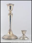 A silver hallmarked candlestick together with a smaller silver hallmarked candlestick.