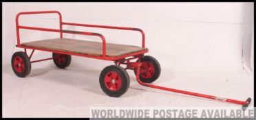 A stunning retro pull along Trolley of red painted tubular construction, with a wooden base,