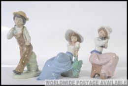 A collection of three Nao ceramic figure groups to include a young boy and his knap sack along with