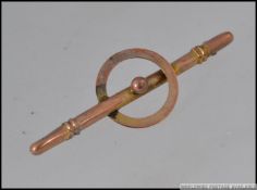 A vintage yellow metal bar brooch with central overlapping ring. Measures 5cms.