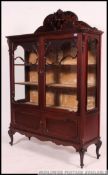 An Edwardian large mahogany bookcase / china display cabinet of rococo form being raised on shaped
