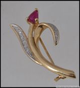 A 9ct gold brooch in the form of a tulip with diamond pave set leaves and a central ruby flower