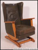 A reto mid 20th Century American sprung rocking chair / armchair with green leather padded wing