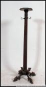 A Victorian carved mahogany torchere of ebonised form raised on carp feet with reeded column having