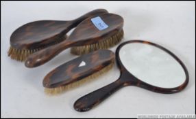 An early 20th century Tortoiseshell 4 piece ladies vanity set to include 3 clothes brushes and a