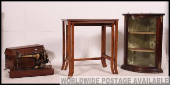 A mahogany bow front small corner display cabinet together with a singer sewing machine in case and