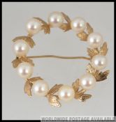 A 14ct gold and pearl ladies brooch of circular form, the pearls intertwined with leaves.
