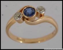 An 18ct gold ring with central blue stone flanked by two 5pt diamonds in bezel settings Marked 18ct