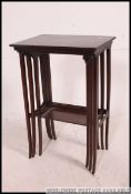 A fine Edwardian mahogany inlaid nest of tables being raised on turned supports united by