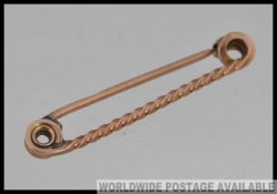A 9ct gold bar brooch with twisted bar and curled finials with finial clasp. Marked 9ct. Weight 3.