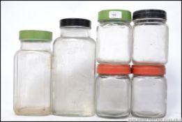 A collection of vintage / retro glass storage jars with different colour screw twist lids