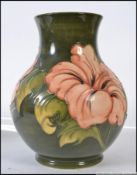A large Walter Moorcroft pattern tubeline decorated vase on green ground with pink flowers,