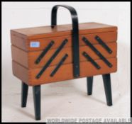 A 1950's retro / vintage metamorphic sewing box with muti action being raised on ebonised tapered