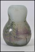 A stunning miniature enamelled glass vase being hand painted with furn trees and lake scene being