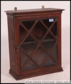 An early 20th century oak wall cabinet having single astragal glazed door front