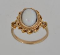 A 9ct gold ring hallmarked London with a white cabochon stone in a rope twist setting. Size N.
